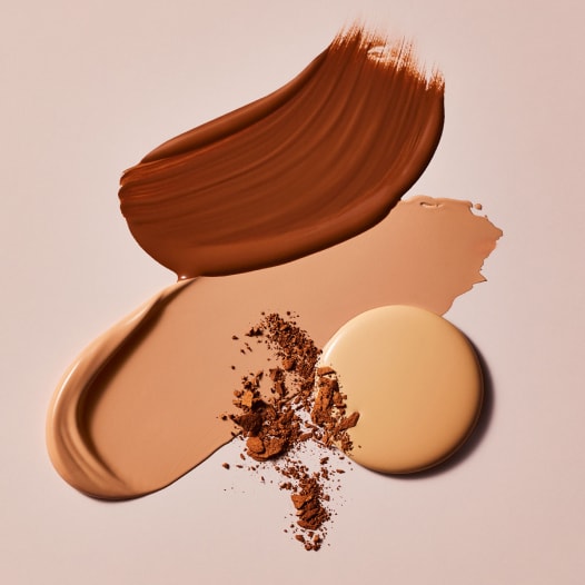 different estee lauder foundation textures on a smooth beige surface