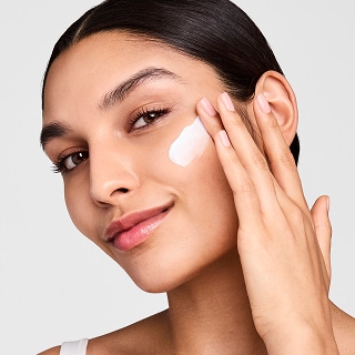 woman applying estee lauder revitalizing supreme moisturizer for beginners skincare routine